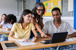 © Xavier Lorenzo - Mid adult female teacher helping diverse high school students in classroom. Education lifestyle concept