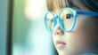 © Steve - Young child wearing blue glasses focusing on distant tree outside window, symbolizing myopia prevention and importance of outdoor activities.