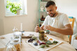 © Aleksandr - Handsome bearded man adds dried herbs to a mortar and pestle. Homemade healthy and nutrition supplements