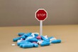 © Gosia - Drug addiction; stop taking so many medications; stack of multi-colored pills with a stop sign