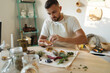 © Aleksandr - Handsome man in an apron sits at the table and preparing healthy and nutrition herbal tea