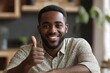 © James - Happy african american young man sitting at table in shirt and showing thumb up gesture remotely from home, selective focus, Generative AI