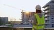 © volha_r - Construction female engineer taking notes and writing on clipboard while inspecting a building site at sunset. Industry development concept