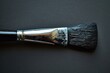 © juliars - Well used paint brush is lying on a black surface, covered in black paint