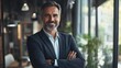 © Johannes - Happy middle aged business man standing in office arms crossed wearing a suit and shirt, Generative AI