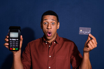 Sticker - Photo of excited positive guy dressed brown shirt showing bank card terminal isolated blue color background