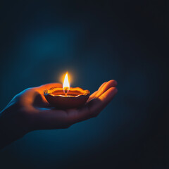 Photograph of a person holding a diya (lamp) on a dark blue background