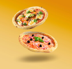 Different pizzas in air on orange gradient background