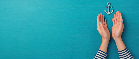 Stylish hands holding an anchor against a vibrant teal background, symbolizing strength, hope, and stability by the sea.