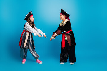 Poster - Full size photo of two small kids dancing halloween pirate costume isolated on blue color background