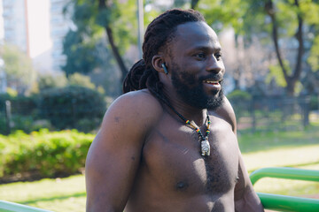 Black man laughing in the park while exercising, enjoying the healthy morning.