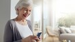 © Bonsales - Cheerful senior woman using smartphone at home, enjoying technology while connecting with family and friends through social media.