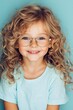 © Kittipong - Captivating Close-Up Portrait of Smiling Girl with Gold-Rimmed Glasses on Blue Background - Innocence and Beauty Concept