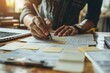 © Valentin - Focused Professional Working on Documents with Laptop and Sticky Notes