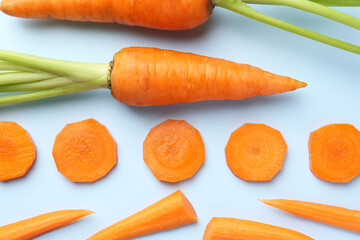 Wall Mural - Whole and cut fresh carrots on light background, flat lay