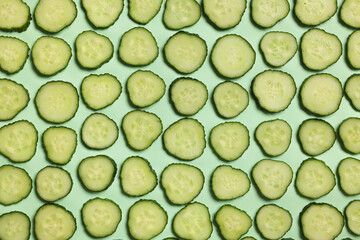 Poster - Slices of fresh cucumbers on turquoise background, flat lay