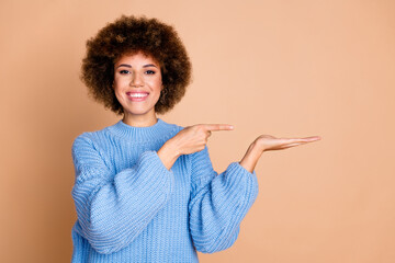 Canvas Print - Photo of nice girl with chevelure dressed blue knit sweater directing at product on palm empty space isolated on pastel color background