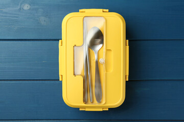 Poster - Yellow lunch box with cutlery on blue wooden table, top view