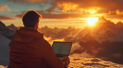 Poster - A man with short-cropped brown hair sitting at a caf on the edge of a mountain, typing on his laptop as the sun sets behind the peaks. The golden light and the dramatic view create a magical,