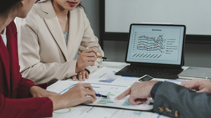 Business team analyzing financial charts and graphs on digital tablet and reports during a meeting in a modern office