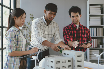 Wall Mural - architects team is working on an eco friendly building project together, using a model and digital t