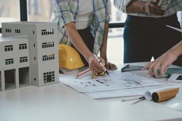 Wall Mural - architects team working together on a project in the office using a blueprint and pointing at it wit