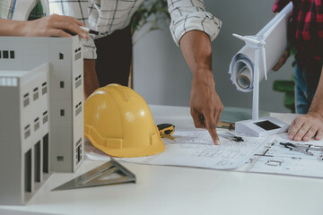 Architects are having a meeting in their office, examining blueprints and a building model