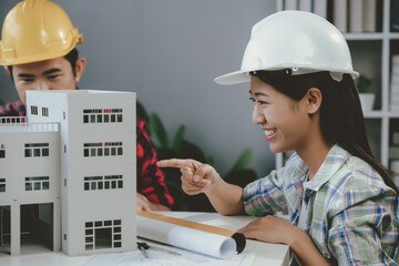 Wall Mural - two architects are smiling while working on a model of a building project in their office