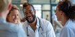 © Svetlana Leuto - An African-American male doctor in a white coat talks to colleagues and laughs, a team of smiling doctors in uniform against the background of a hospital corridor