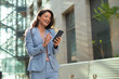 © Dexon Dee - Successful business woman using phone outdoors. Happy businesswoman walking outdoor with phone in hands