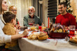 © Mediteraneo - Happy family having Christmas dinner with their grandparents. Eating homemade food, drinking beverages. Home is decorated for New Year's Eve and Christmas