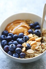 healthy vegan protein quinoa bowl, topped with fresh blueberries, creamy peanut butter, and a drizzle of almond milk, presented in a white bowl with a spoon,