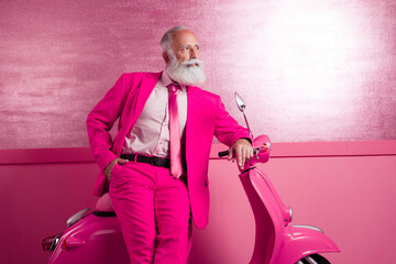 Photo of attractive charming mature grandfather macho stand motor bike posing look empty space pink color wall in interior wear blazer