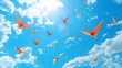 © Nicat - Floating origami cranes flying through a bright blue sky filled with clouds.