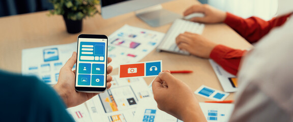 Panorama banner of startup UX developer or company employee design user interface or UI prototype for mobile application or website software with software display on smartphone in office. Synergic
