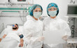© My Ocean studio - Two healthcare workers in full protective gear hold blank paper in a hospital room, with patient in the background on oxygen support, highlighting medical care, safety, and healthcare communication