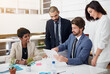 © ThurstanJam/peopleimages.com - Corporate, collaboration and group with tablet, boardroom and conversation for financial report and confident. Pointing, teamwork and people with paperwork, plan and project for actuary and meeting