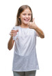 © Krakenimages.com - Young beautiful girl drinking glass of water over isolated background happy with big smile doing ok sign, thumb up with fingers, excellent sign
