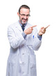 © Krakenimages.com - Middle age senior hoary professional man wearing white coat over isolated background smiling and looking at the camera pointing with two hands and fingers to the side.
