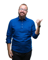 Wall Mural - Young caucasian hipster man wearing glasses over isolated background smiling with happy face looking and pointing to the side with thumb up.