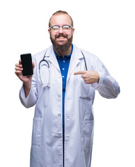 Wall Mural - Young doctor man showing smartphone screen over isolated background with surprise face pointing finger to himself