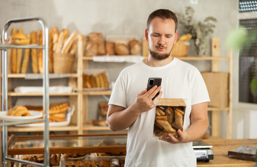 Young male shopper checks calories of cookies using app on his phone