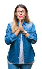 Canvas Print - Young beautiful woman over wearing glasses over isolated background praying with hands together asking for forgiveness smiling confident.