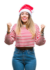 Wall Mural - Young beautiful woman wearing christmas hat over isolated background celebrating surprised and amazed for success with arms raised and open eyes. Winner concept.