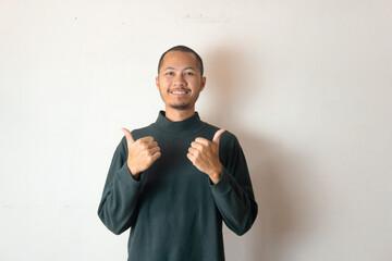 Young men wearing winter clothes smiling with thumbs up on isolated white background