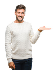 Sticker - Young handsome man wearing winter sweater over isolated background smiling cheerful presenting and pointing with palm of hand looking at the camera.