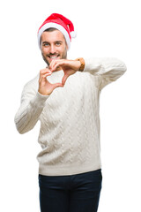 Canvas Print - Young handsome man wearing santa claus hat over isolated background smiling in love showing heart symbol and shape with hands. Romantic concept.