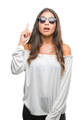 Wall Mural - Young beautiful arab woman wearing sunglasses over isolated background pointing finger up with successful idea. Exited and happy. Number one.