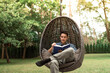 © kieferpix - Young man reading a book relaxing in a comfy chair lounge in a green nature setting enjoying weekend holiday