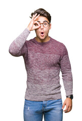 Wall Mural - Young handsome man wearing glasses over isolated background doing ok gesture shocked with surprised face, eye looking through fingers. Unbelieving expression.